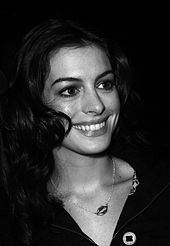 The black-and-white picture shows Anne Hathaway smiling to her right.
