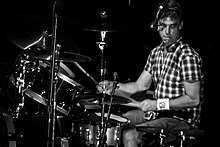 A male drummer, Matt Cameron, seated behind a drumkit of drums and cymbals.