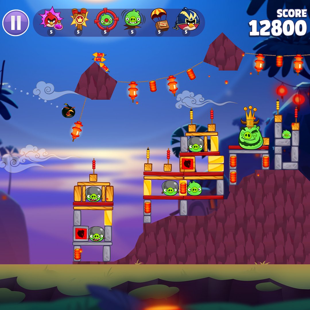 A screenshot from Angry Birds: Reloaded showing a bird getting launched towards a group of pigs, including one wearing a crown.