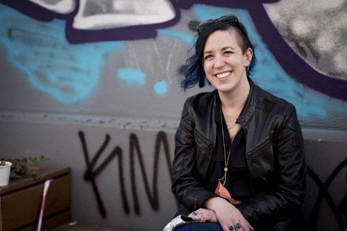 Portrait of Jillian C. York, in front of a wall of Berlin graffiti