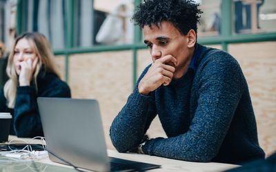 Serious worried colleagues with laptop on desk sitting in office