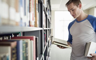Male student choosing books in college library