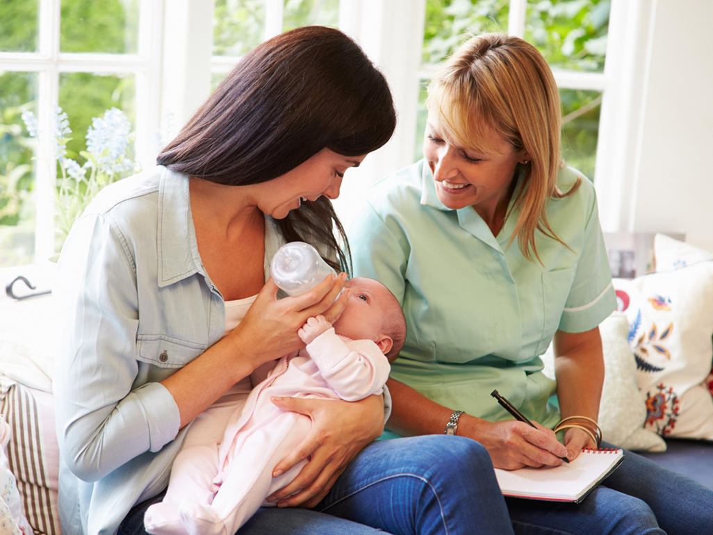 woman monitoring mother feeding a baby