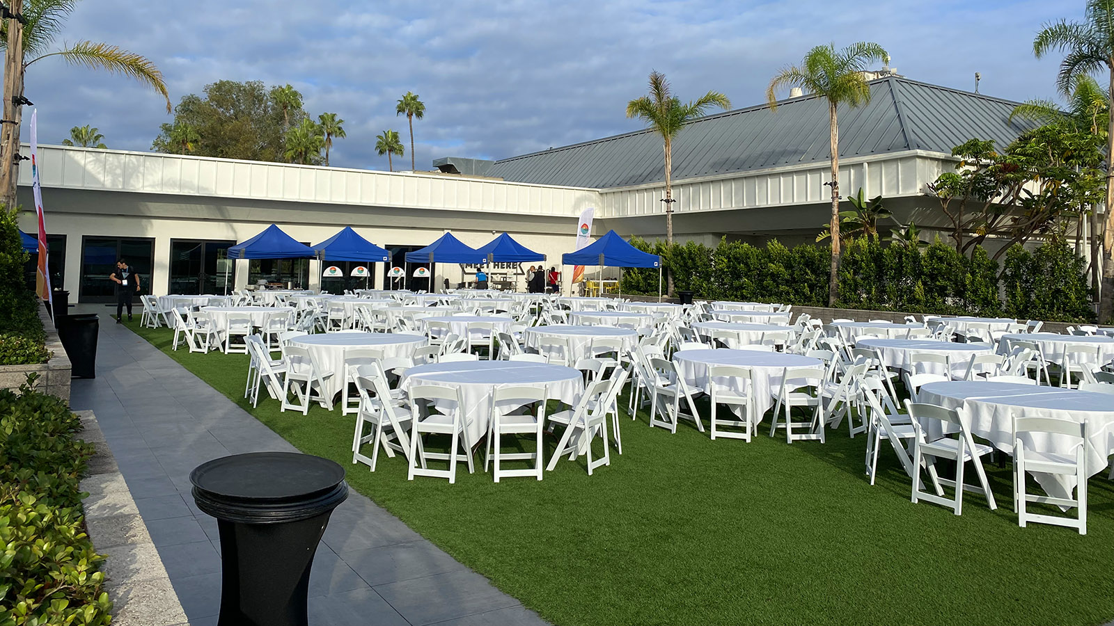 WordCamp US dining area with tables and chairs and five blue tents the Flaming Lawn, Town and Country San Diego. Shared by Jörg Strotmann