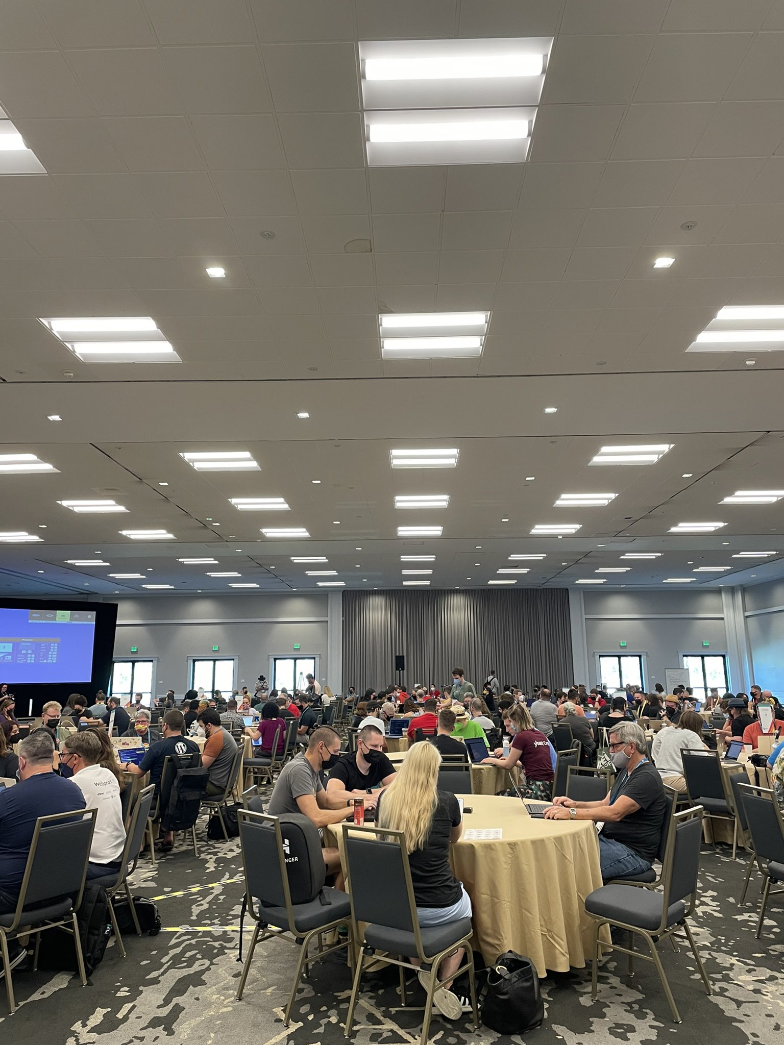 Multiple groups of people sit around various circular tables