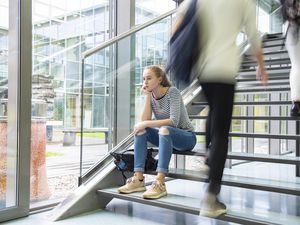 Lonely girl sitting on stairs at college.