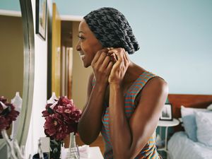 Smiling African American woman attaching earring