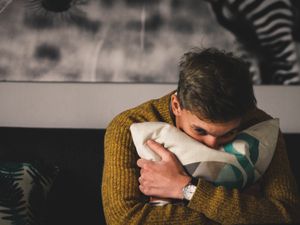 depressed person holding a pillow while crying