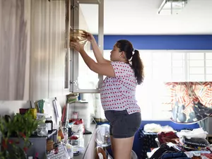 Woman storing pots in a cupboard