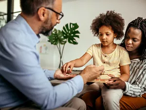 Little girl choosing toy with male psychologist
