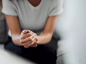 person in therapy session holding their hands