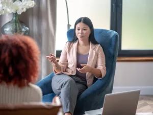 Asian professional female psychologist speaking with client