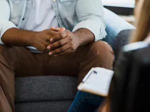 Focus on man's clasped hands during counseling session