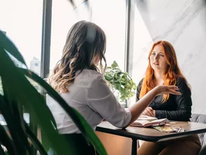 A client talking to their therapist. The client is listening to the therapist intently.