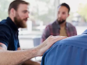 White man with hand on friend's shoulder.