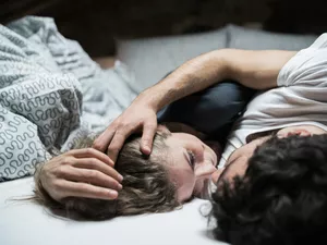 Young couple lying in bed embracing face to face