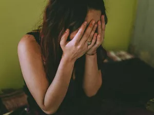 Sad Woman With Hands Covering Face Sitting At Home