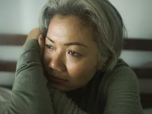 mature lady crisis - attractive middle aged woman with grey hair sad and depressed in bed feeling scared and lonely thinking worried about covid-19 virus pandemic during home lockdown