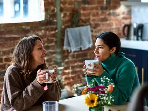 Female friends sitting in cafe with mug of coffee, talking, support, friendship