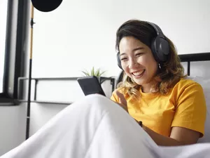 Woman reading from her smart phone in bed, smiling