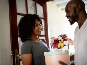 Husband surprising his wife with a flowers and present at home