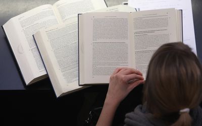 Woman reading from several books open in front of her