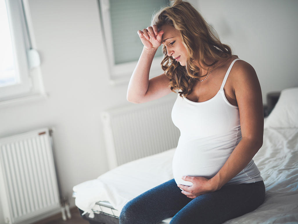 pregnant woman sitting on a bed