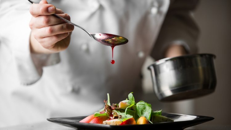 A chef put dressing on a salad