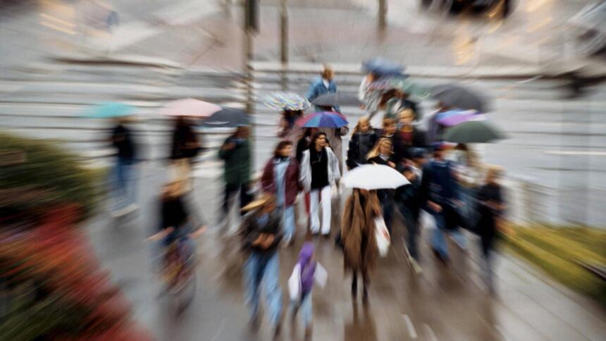 Menschen mit Regenschirmen auf einer Kreuzung