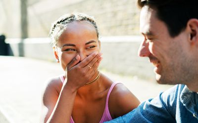 Woman in pink dress laughing at something male companion says