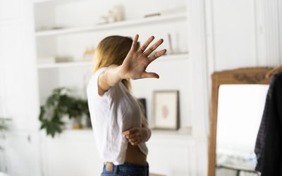 woman holding her hand out to the camera covering her face