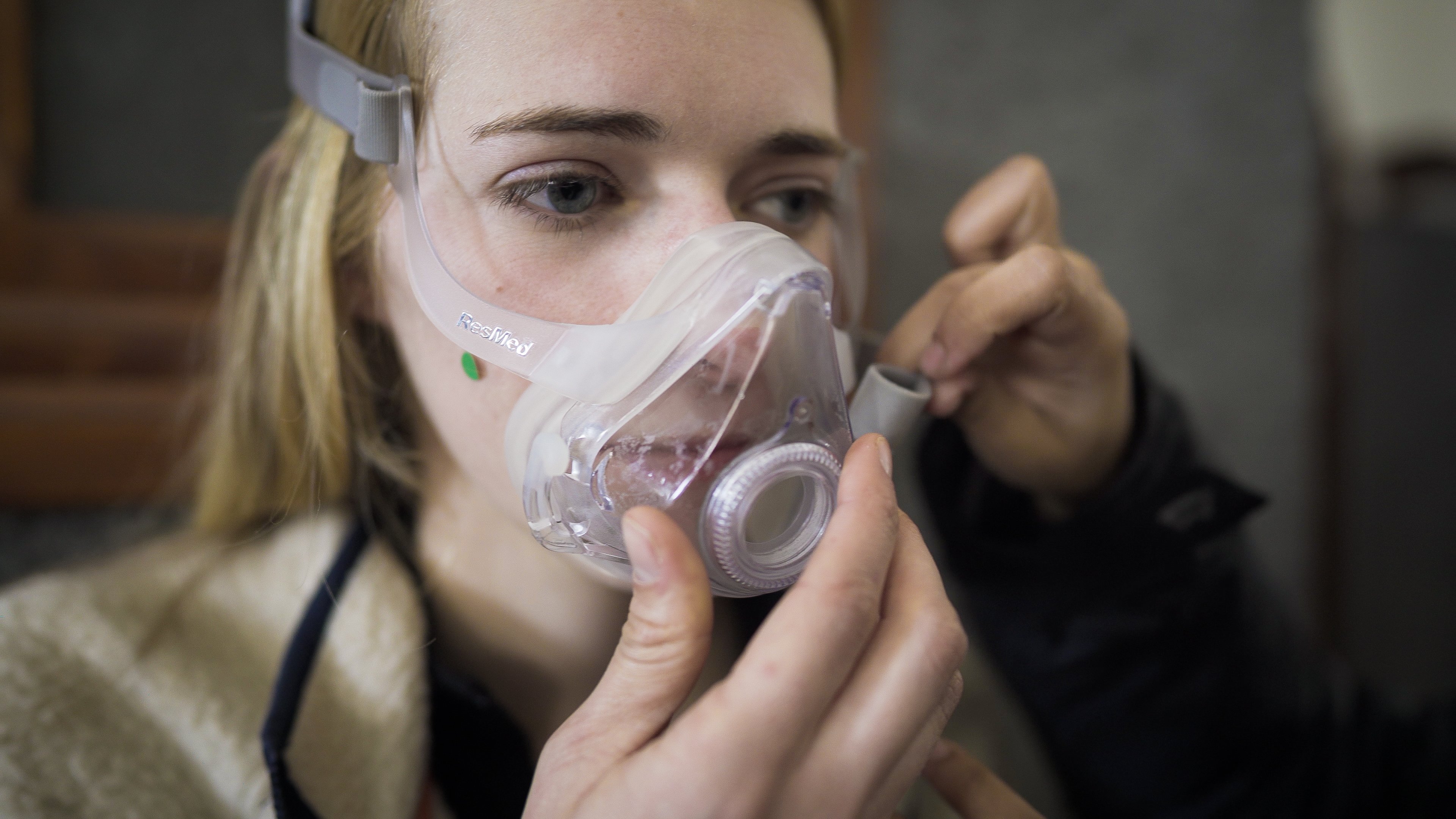 Student wears a full face RedMed mask as another student adjusts the side