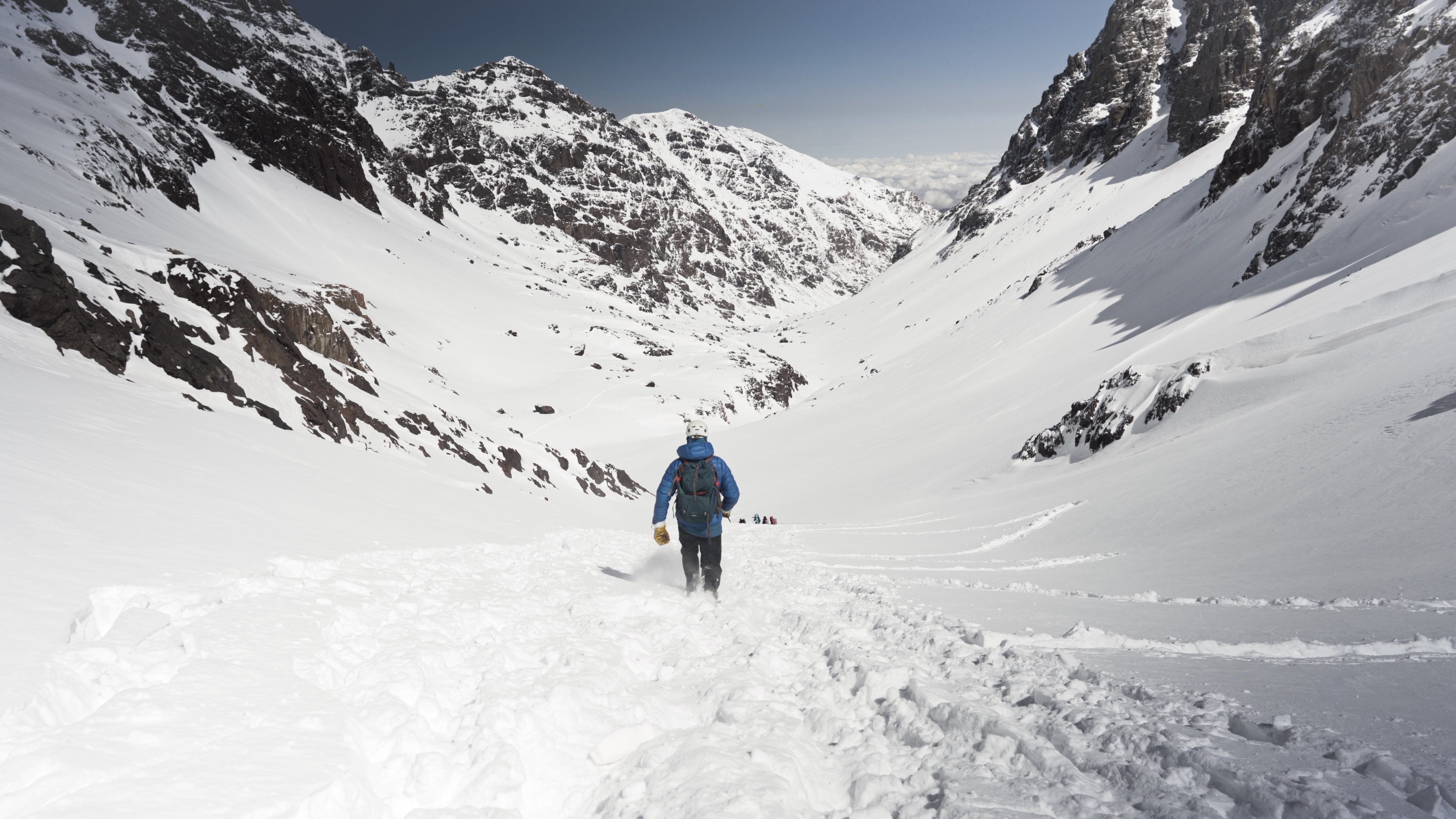 Research expedition group walk down a snowy mountain, more mountainous terrain can be seen in the distance