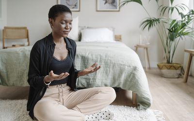 person meditating on the floor of their bedroom