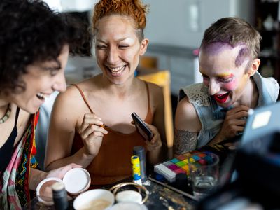 Friends putting on makeup in preparation for pride parade