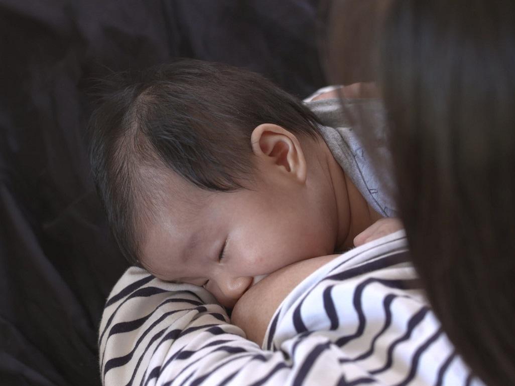 Baby mit geschlossenen Augen trinkt an der Brust