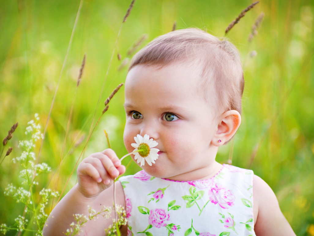 baby in a field smelling flower