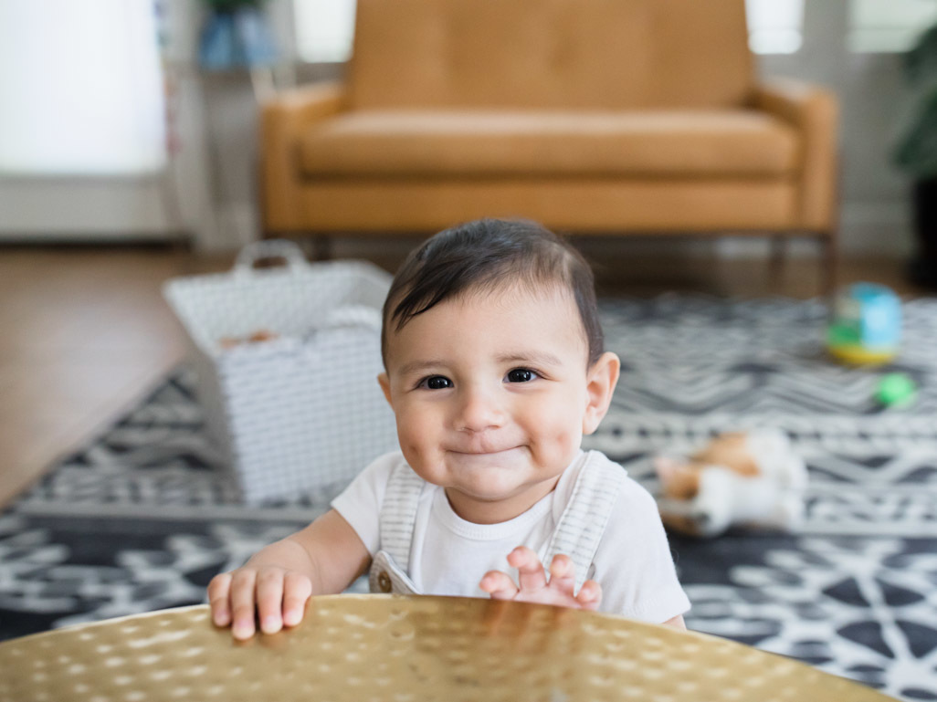 older baby happily standing on their own 