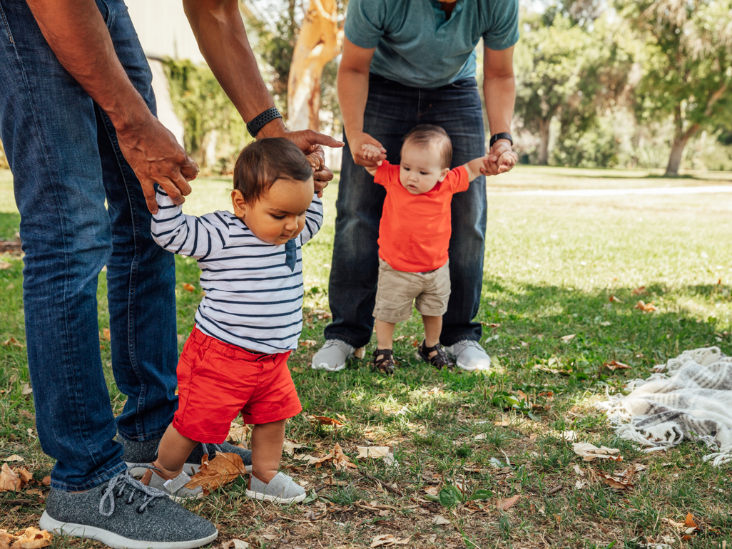 dads with babies holding their hands to help them walk