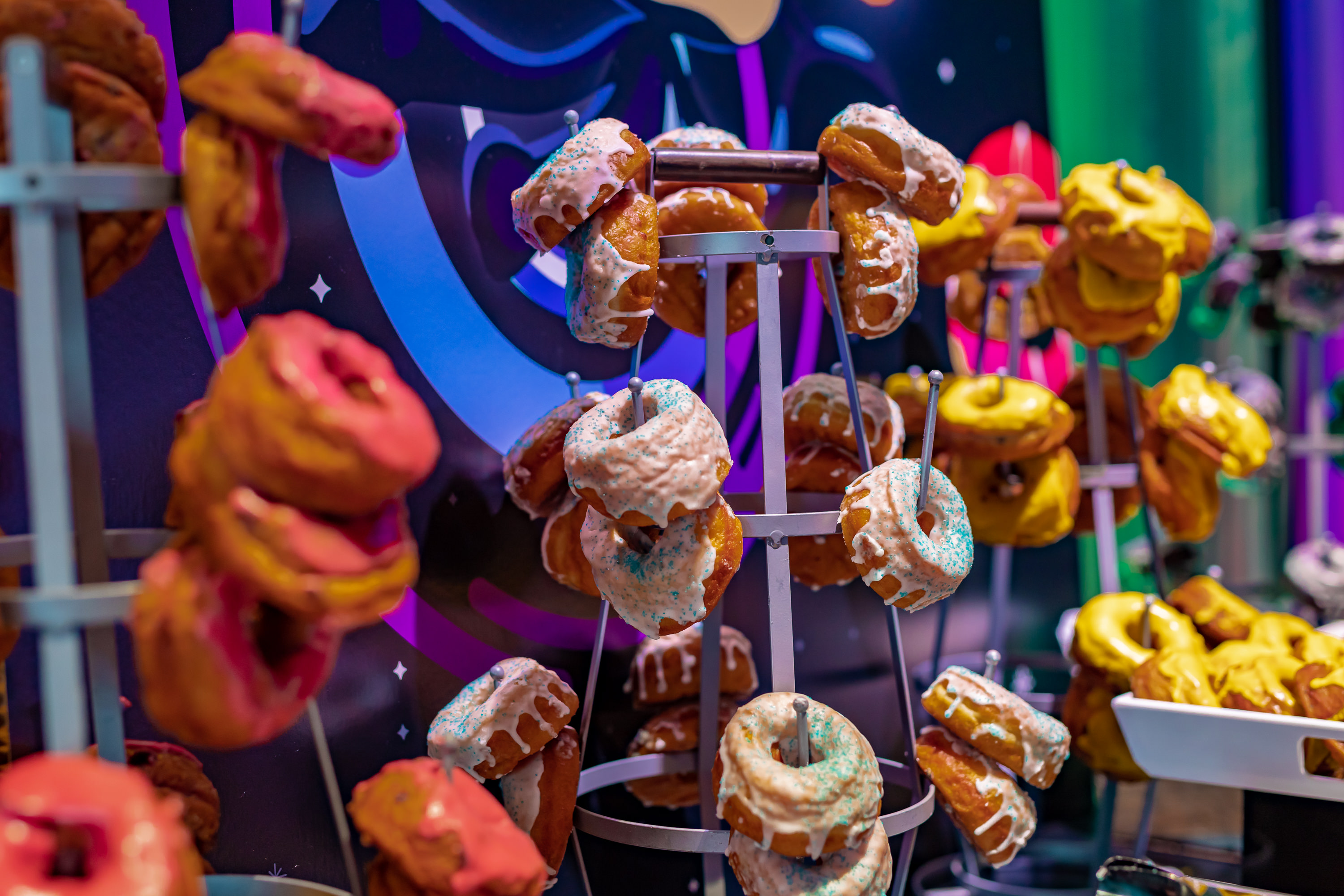 A close up shot of a stand full of donuts with white icing and sprinkles. 