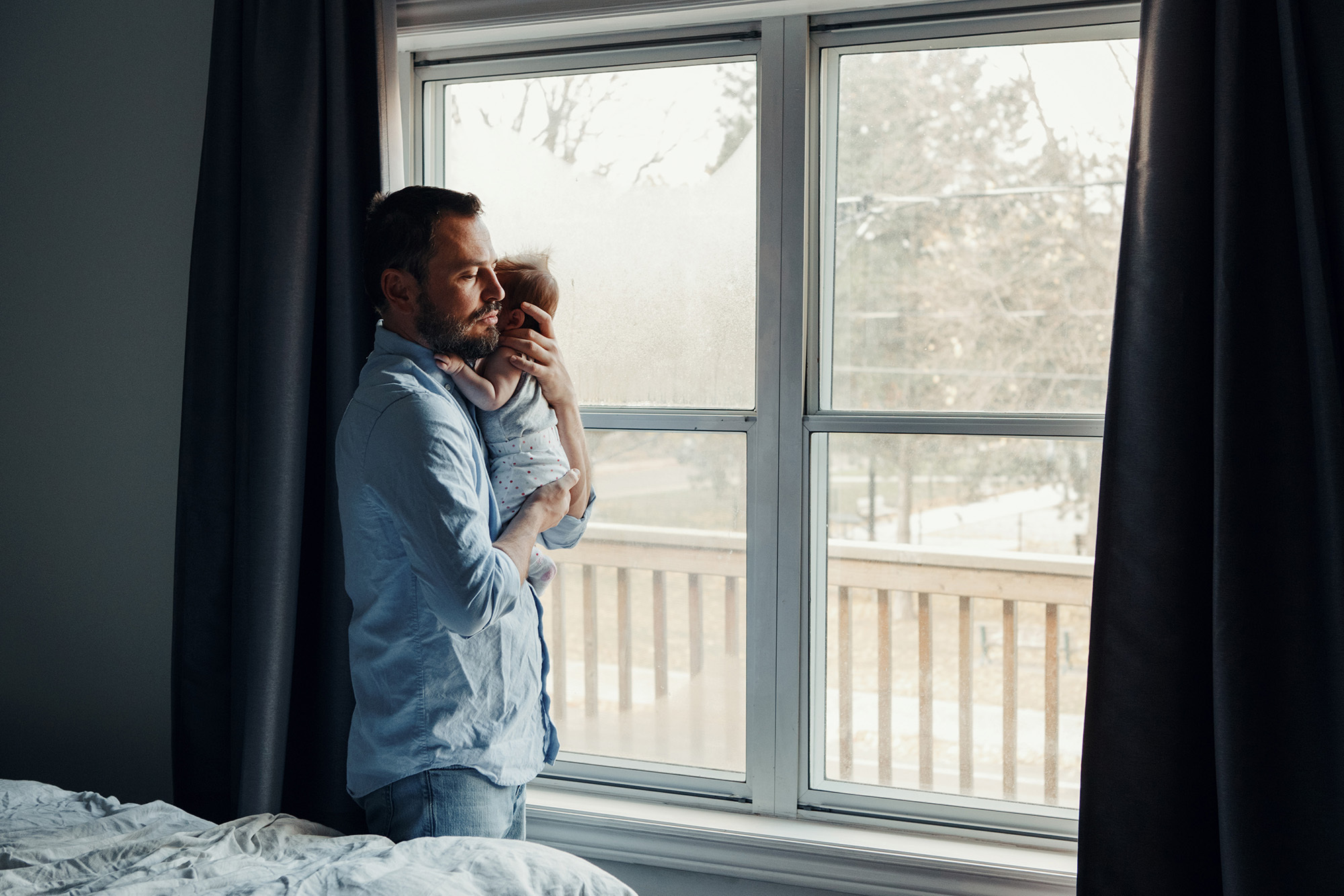 Middle age Caucasian father trying to calm down newborn baby. Man parent holding rocking child on his hands. Authentic lifestyle family moment. Single dad home life concept.