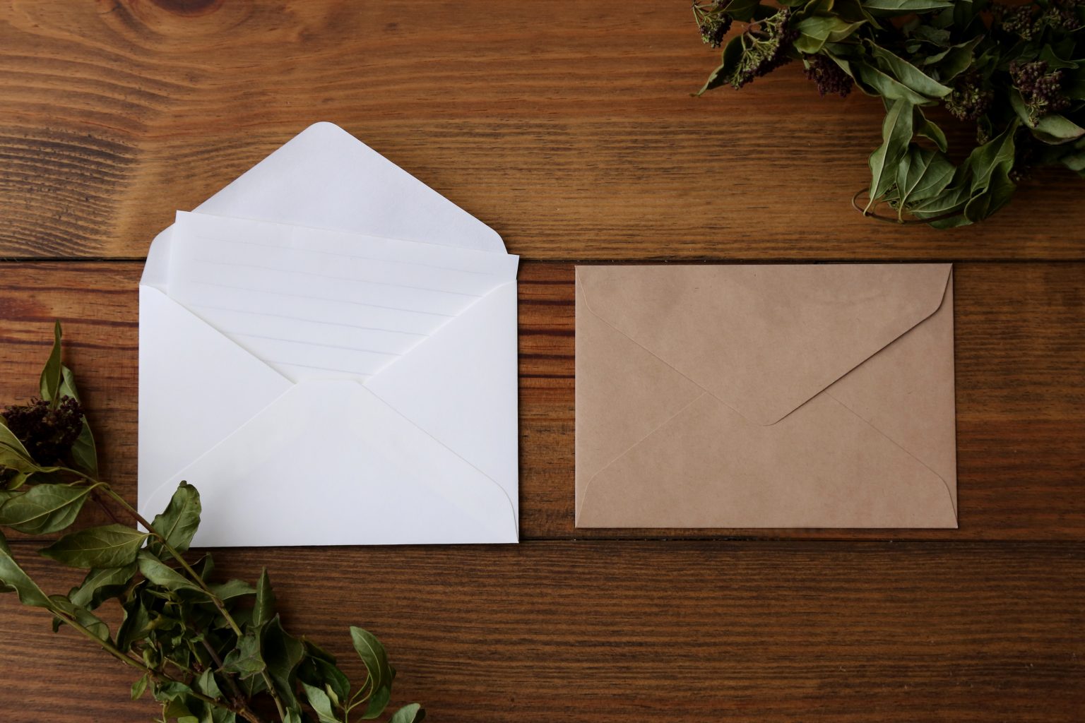 Two envelopes on a wooden surface with dried leaves. One of the envelopes is open with a sheet sticking out. Photo contributed by kaorock72 to the WordPress Photo Directory.