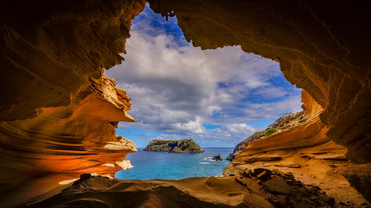 From the inside of a cave, a small island sits a short distance away