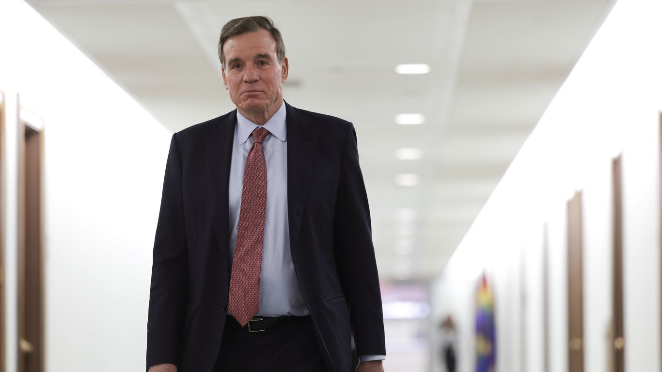 Senator Mark Warner of Virginia walks down a Senate hallway