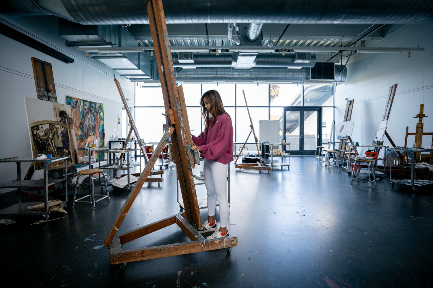 A student paints on an easel in an art studio on campus