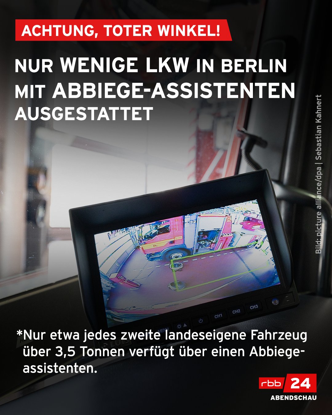 Das Bild zeigt den Monitor eines Abbiege-Assistenten, der an einem Feuerwehr-Löschfahrzeug befestigt ist. Der Bildtext lautet: Achtung, Toter Winkel! Nur wenige Lkw in Berlin mit Abbiegeassistenten ausgestattet. Nur etwa jedes zweite landeseigene Fahrzeug über 3,5 Tonnen verfügt über einen Abbiegeassistenten.