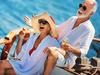 Closeup side view of mid 60's couple enjoying a sailing cruise during summer vacation at ope sea. They are leaning on deck railing and enjoying the view of the sea and horizon while sipping some wine and laughing.