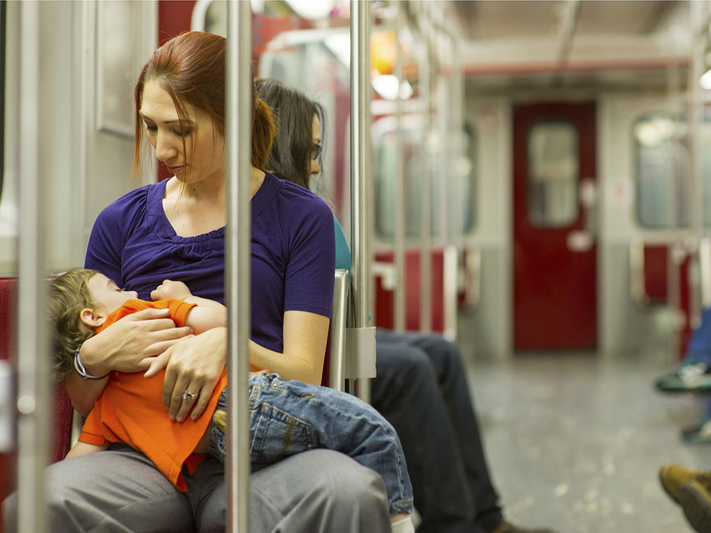 woman in a subway train sitting and holding a sleeping child