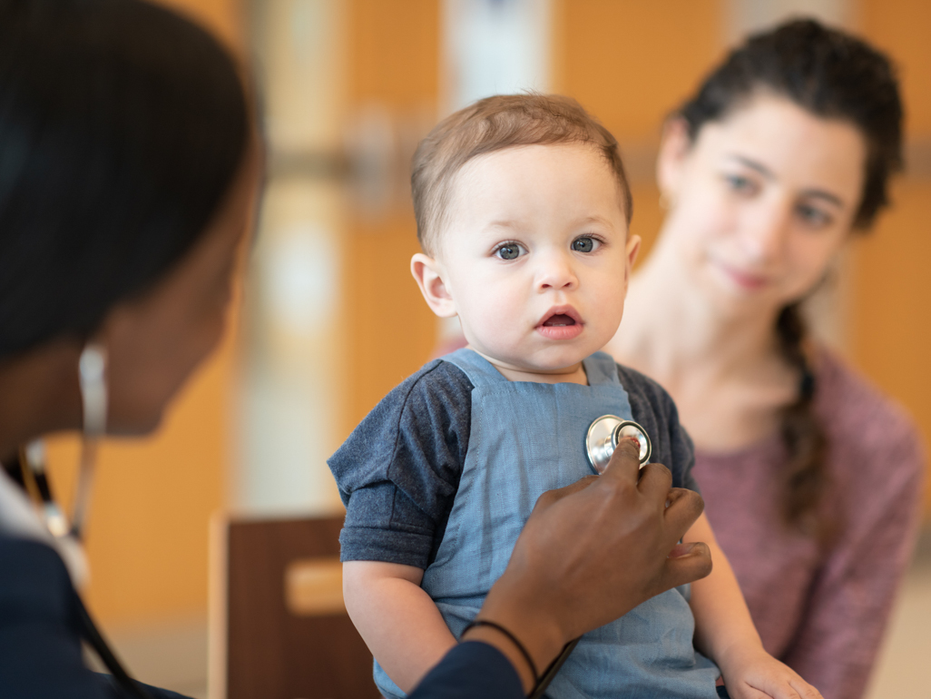 doctor listening to babys chest while mother looks on