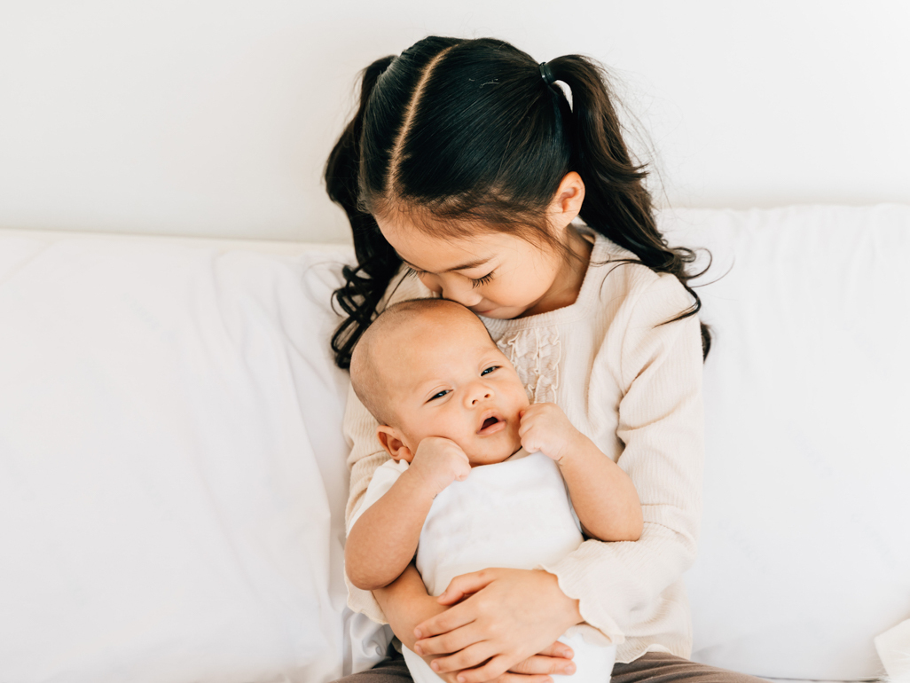 big sister kissing new baby sibling